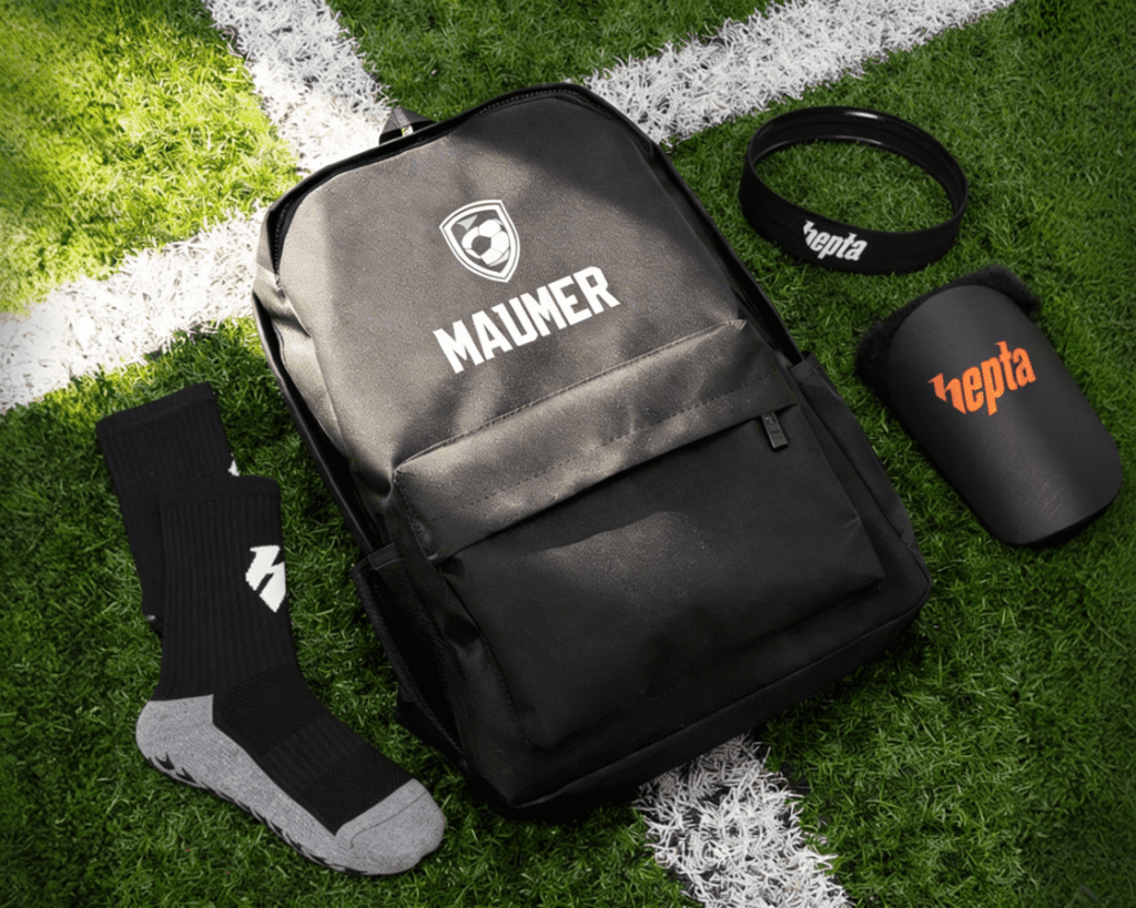 football bags for training and matchday including socks and shin guards on turf field